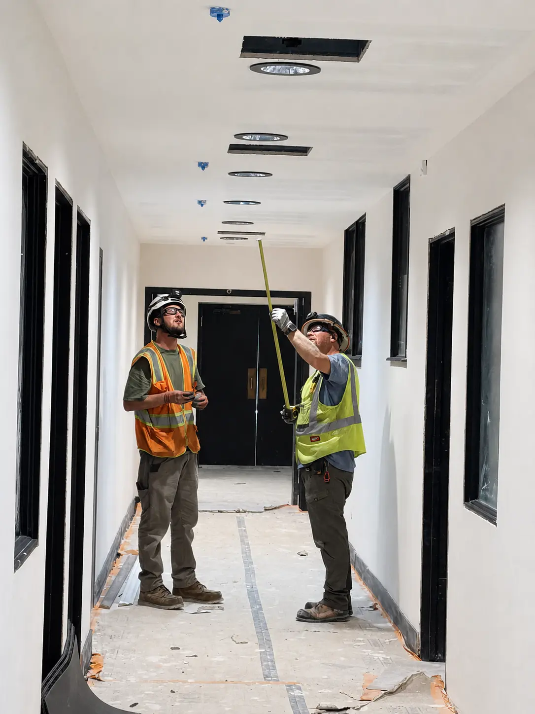 Colpitts Electric electricians measuring recessed lighting locations in a corridor at BRAVE Church in Cherry Hills Village