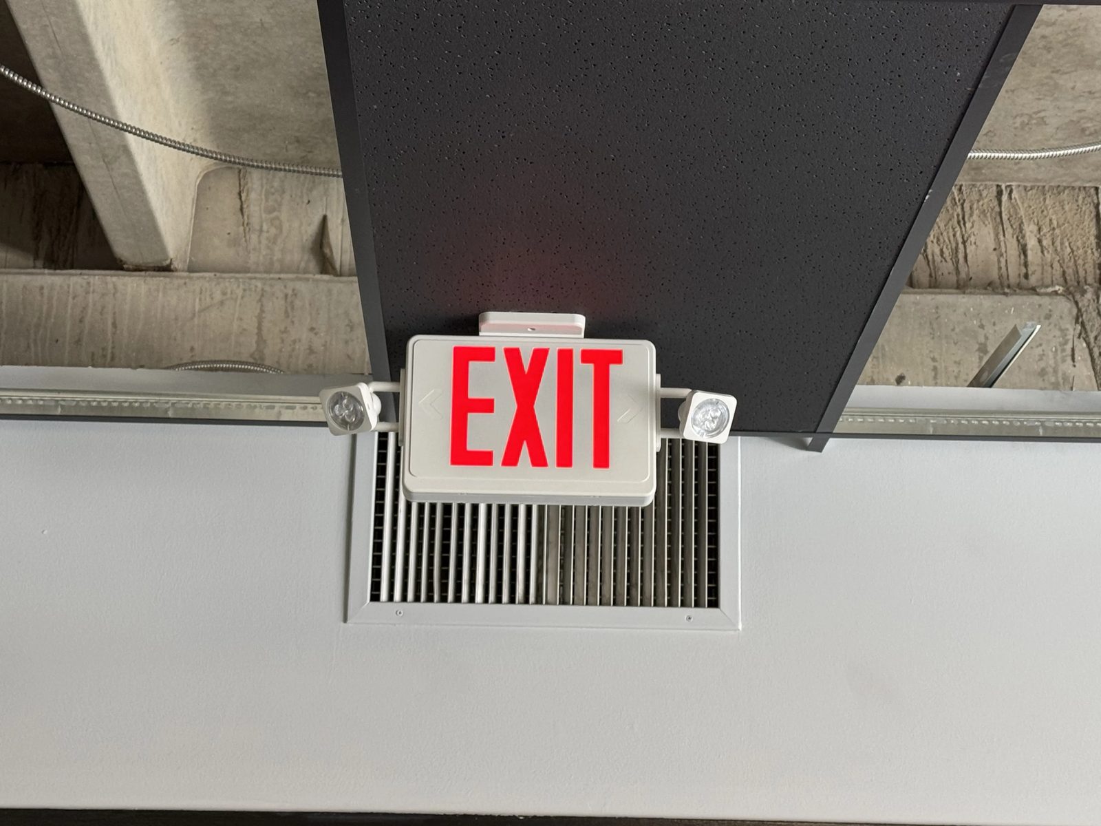 Combination LED exit sign with emergency egress heads on a commercial ceiling